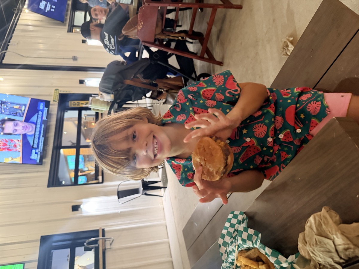 A child holding a burger inside Camp Briteside